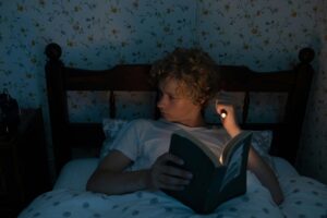 Teenager reading in bed with a flashlight