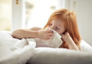 A little girl wiping her nose with a tissue - Indoor Air Quality Hacks for Allergy-Sensitive Households - Quality Home Products of